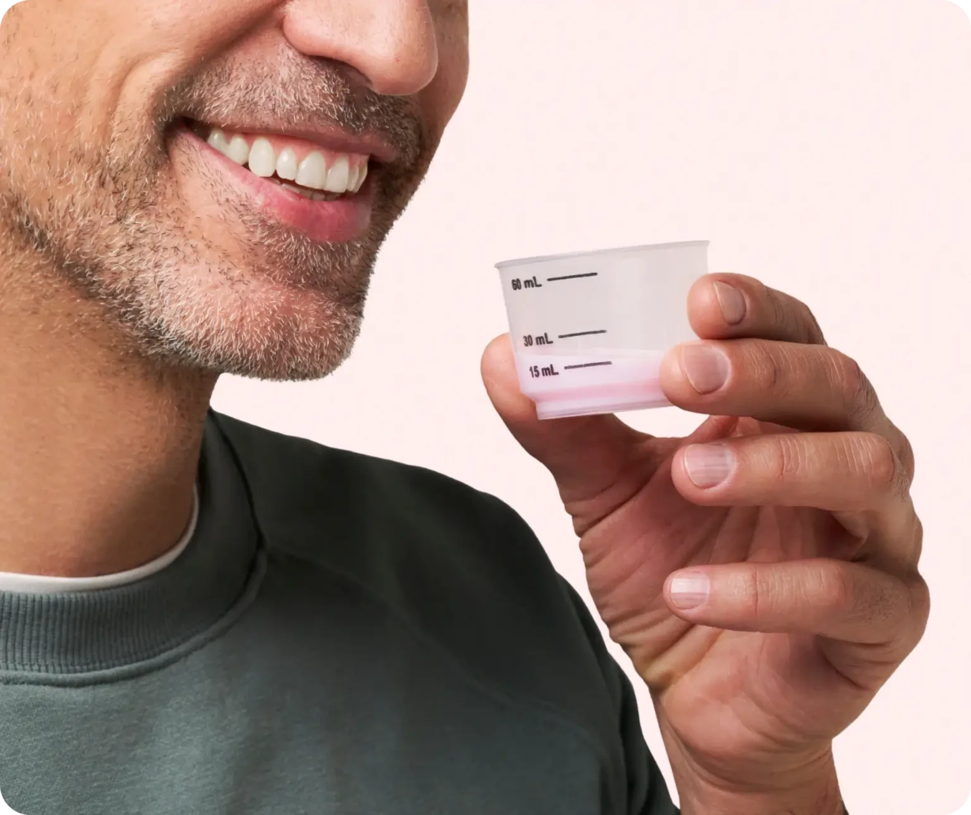 Man smiling while holding a small orange pill near his mouth.